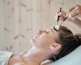 Facial treatment on a lying woman using two brushes