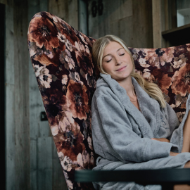 Woman in bathrobe with closed eyes in large chair in the relaxation area of the SPA