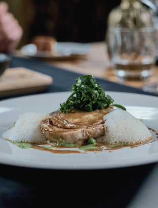 A beautifully presented main course served on a white plate at the dinner table