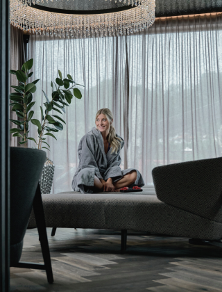 Woman sitting, laughing on a lounger in the relaxation area of the SPA