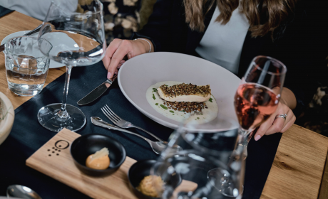 Main course dish with fish, which was served in a deep plate to a woman at the dinner table