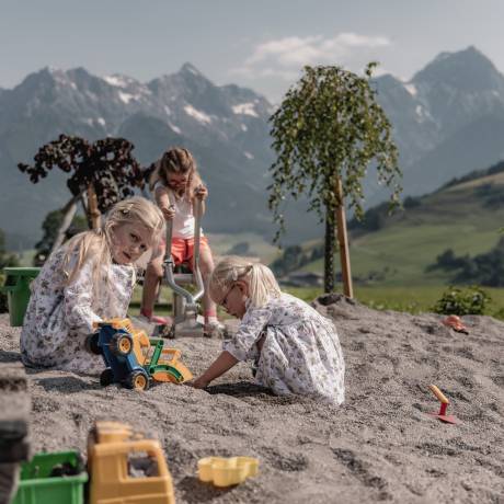 Kinder im Sandkasten mit Blick auf die Berglandschaft