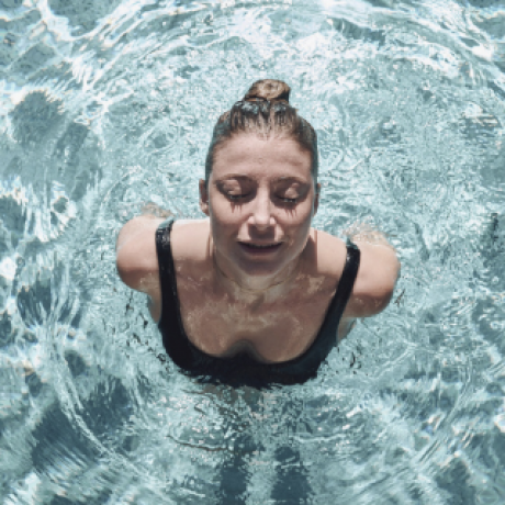 Frau mit geschlossenen Augen beim auftauchen im Pool