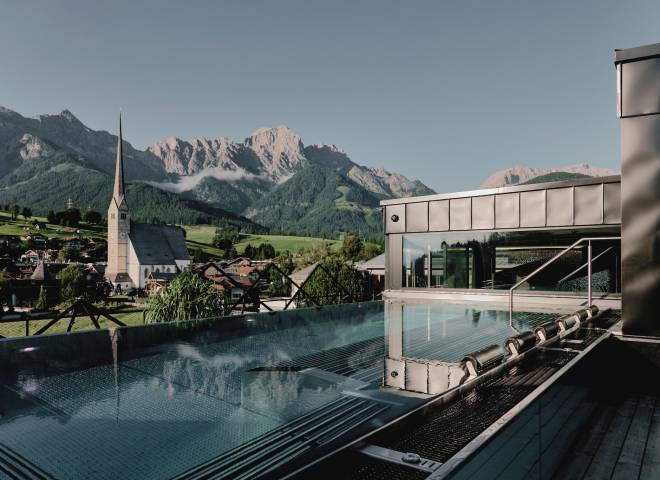 Ausblick vom SPA Fenster der HOCHKÖNIGIN über den Thermalwasserpool auf das Steinerne Meer und den Ort Maria Alm mit seinem Kirchturm