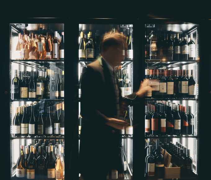 Person in front of a wine fridge in a hotel with different bottles of wine 