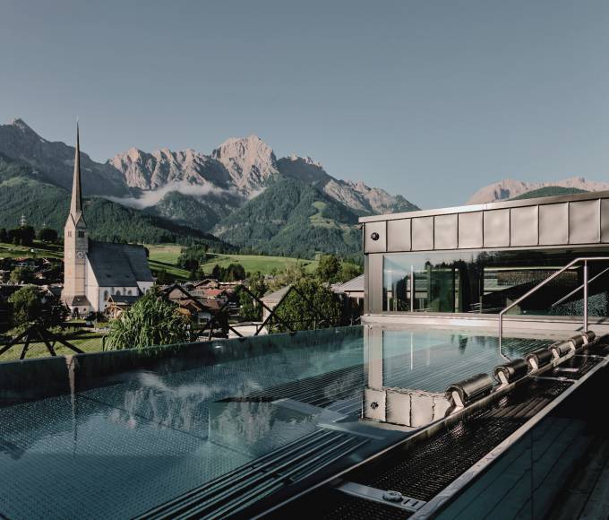 Ausblick vom SPA Fenster der HOCHKÖNIGIN über den Thermalwasserpool auf das Steinerne Meer und den Ort Maria Alm mit seinem Kirchturm